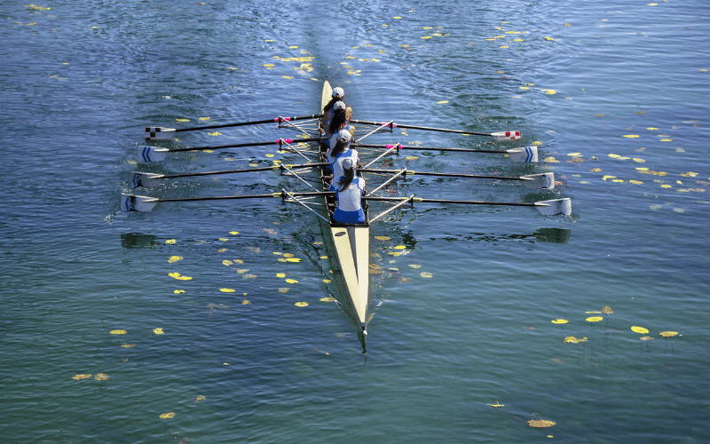 A rowing team discussing sustainability measures for their sport, surrounded by eco-friendly equipment and recycling bins