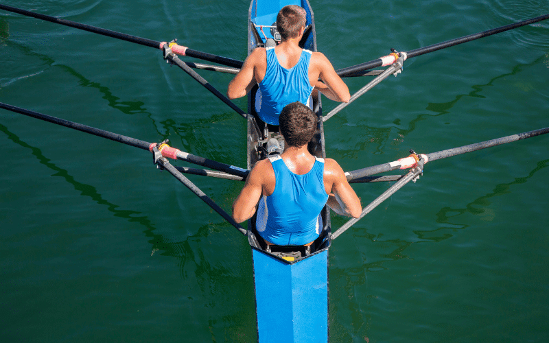 A group of people rowing together on a calm lake, with a focus on teamwork and collaboration. The scene exudes a sense of unity and determination