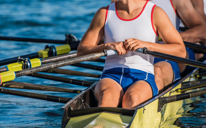 A rowing coach demonstrates injury prevention techniques using equipment and proper form